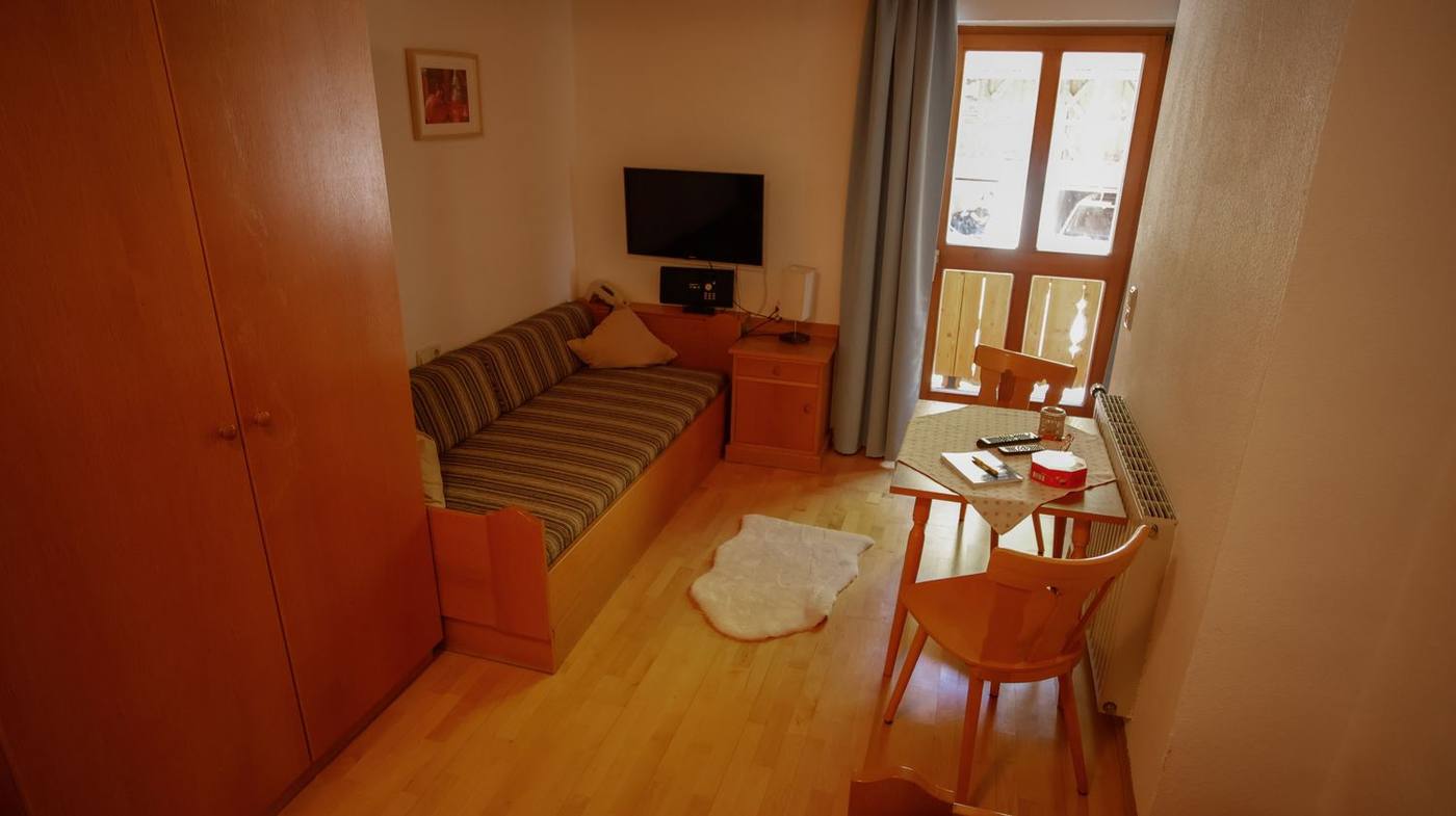 Wohnbereich mit Couch, TV und Esstisch am Fenster
